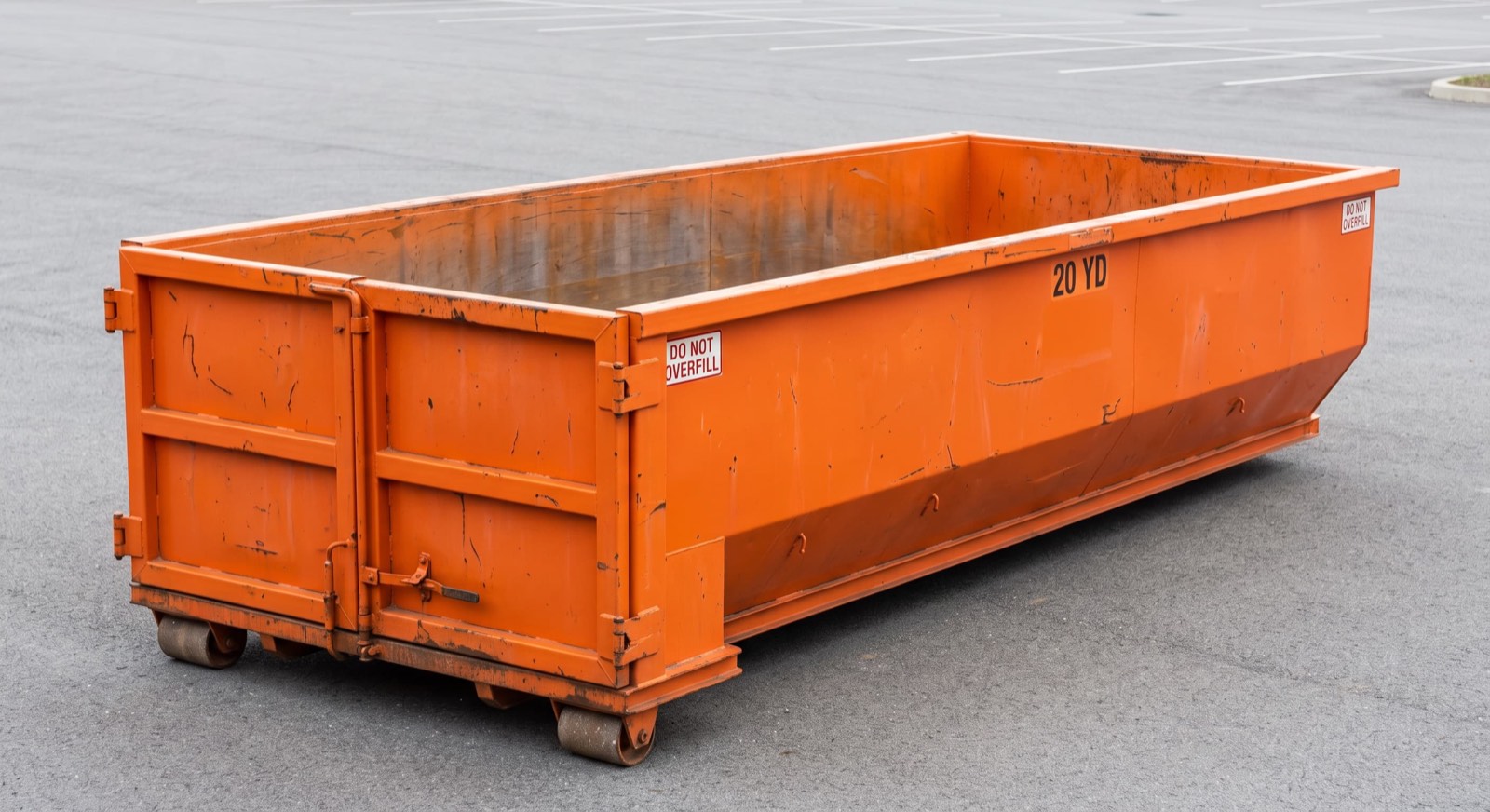 Empty open-top roll-off dumpster container on a paved lot